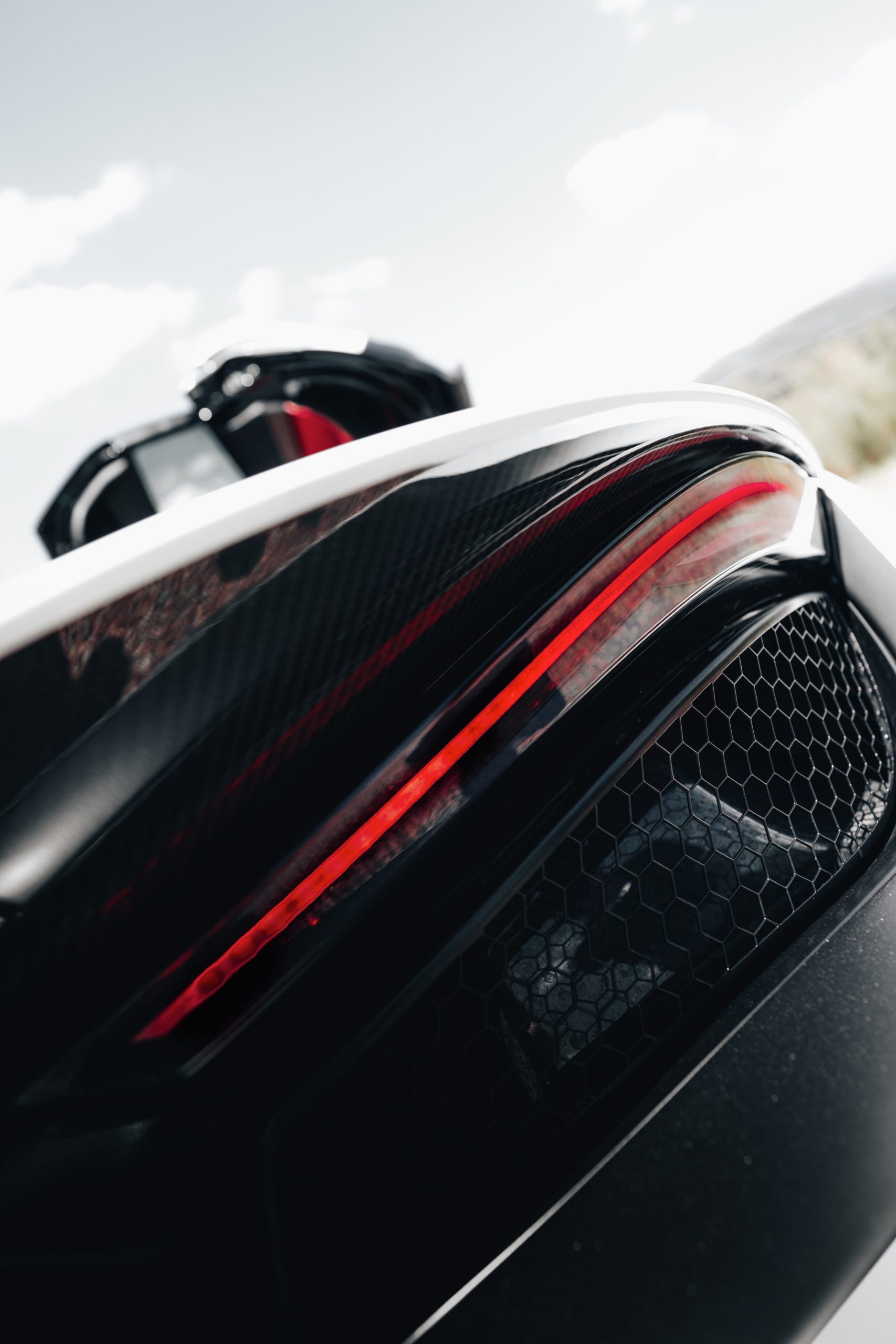 Close-up of rear LED taillight and carbon fibre on a white supercar