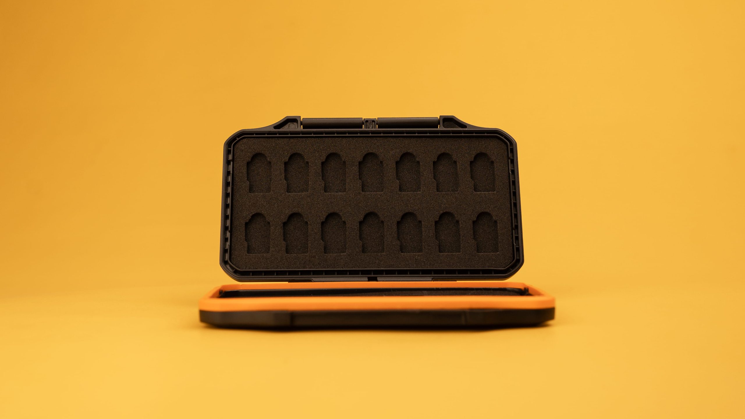 Open rugged black and orange memory card case with foam slots on yellow