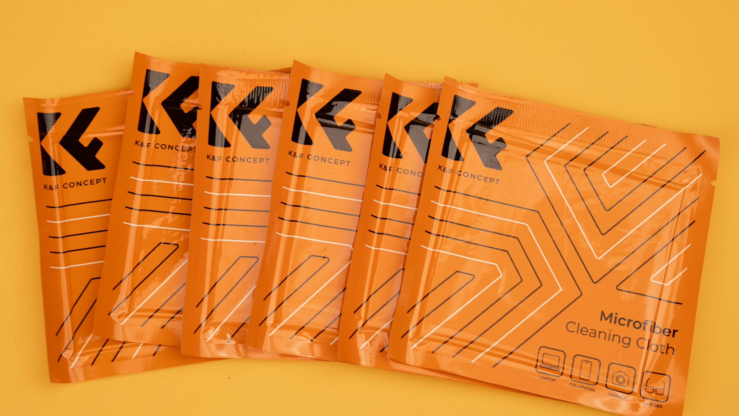 Six orange K&F Concept microfiber cleaning cloth packets fanned on a yellow background